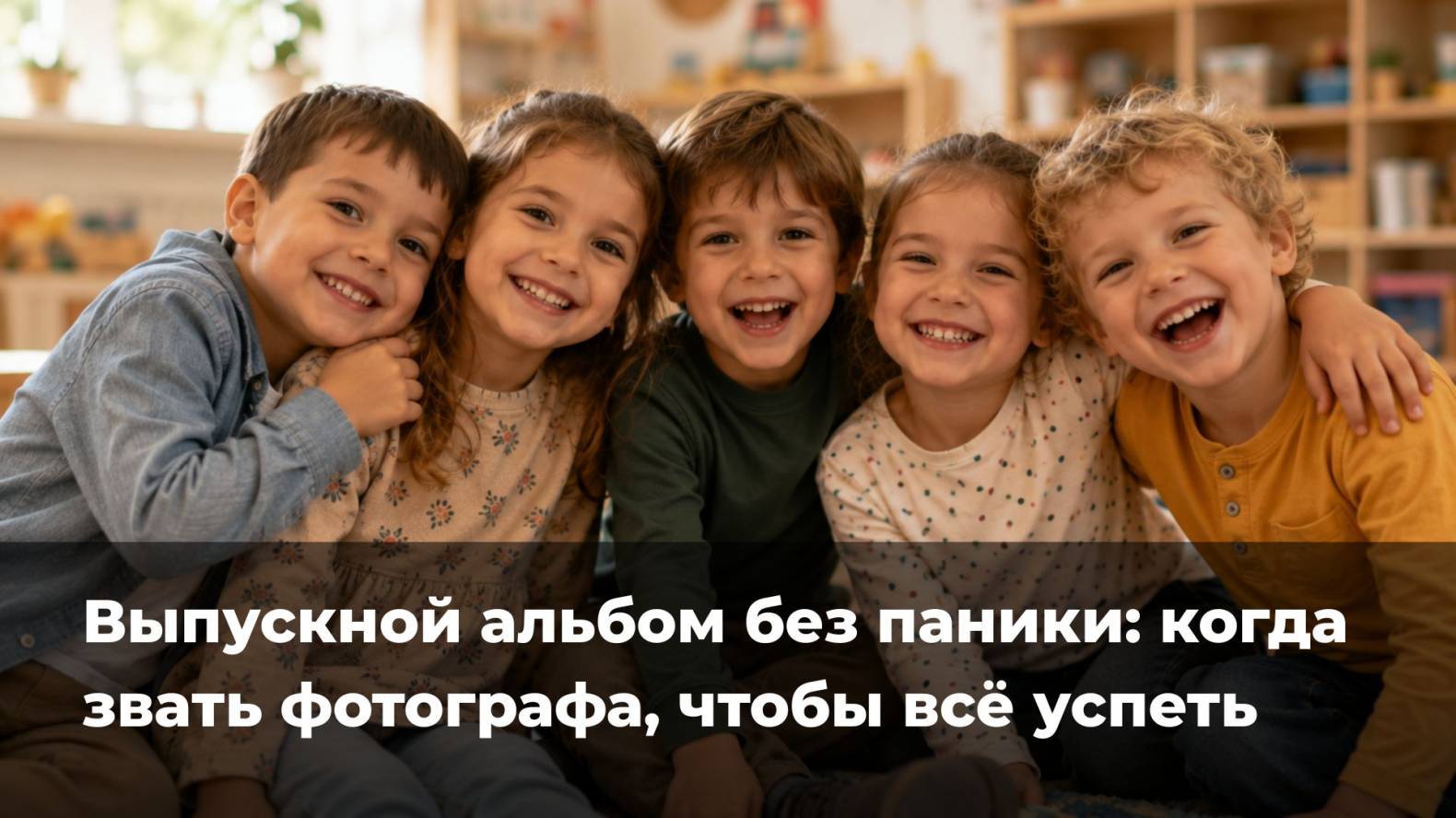 крупный план пяти улыбающихся детей в возрасте примерно 5-7 лет, обнимающих друг друга за плечи. Они находятся в помещении, которое выглядит как детская комната или класс, с полками и игрушками на заднем плане. Дети одеты в повседневную одежду. Все они смотрят прямо в кадр с широкими улыбками. В нижней части изображения находится наложенная текстовая сноска на русском языке. Текст гласит: «Выпускной альбом без паники: когда звать фотографа, чтобы всё успеть». Эта сноска занимает примерно четверть изображения. Фотография яркая, весёлая и фокусируется на лицах детей.